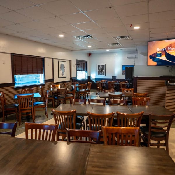 Interior of Blue Eye Bistro, a bar-and-grill, with empty tables and chairs, and a large TV screen.