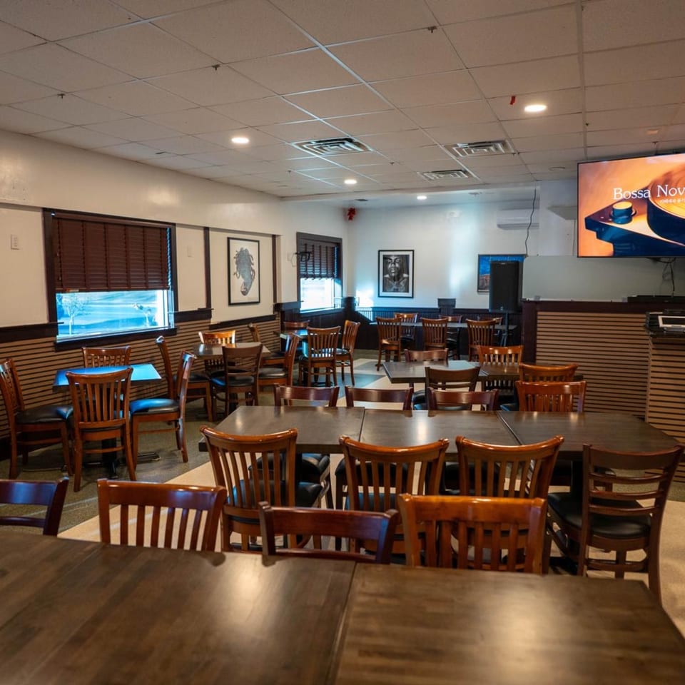 Interior of Blue Eye Bistro, a bar-and-grill, with empty tables and chairs, and a large TV screen.