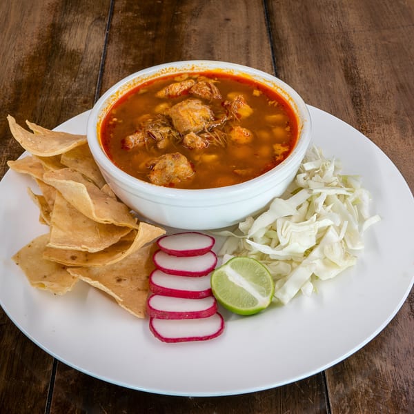 A bowl of Blue Eye Bistro's pozole with tortilla chips, radishes, cabbage, and lime.