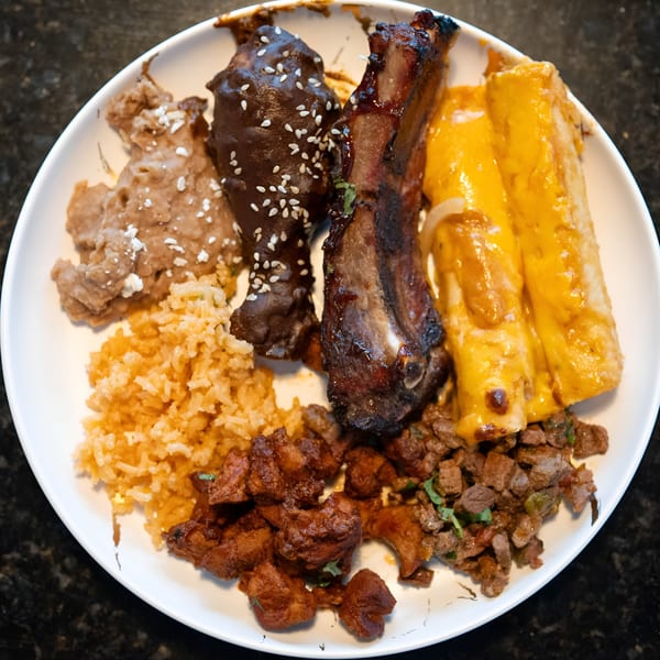 A Blue Eye Bistro platter with ribs, enchiladas, rice, refried beans, and two kinds of meat.