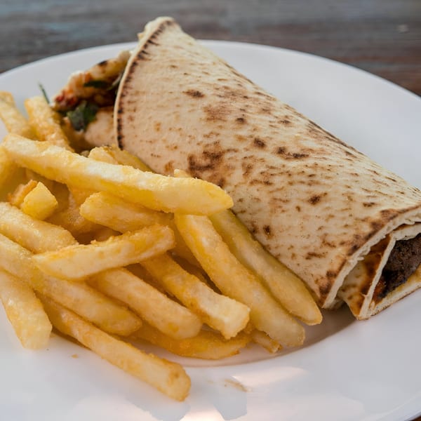 Blue Eye Bistro's grilled wrap with meat and vegetables, served with a side of golden french fries.