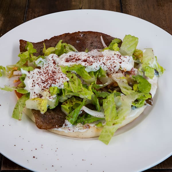 Blue Eye Bistro's gyro with meat, lettuce, onions, and white sauce, sprinkled with red spice.